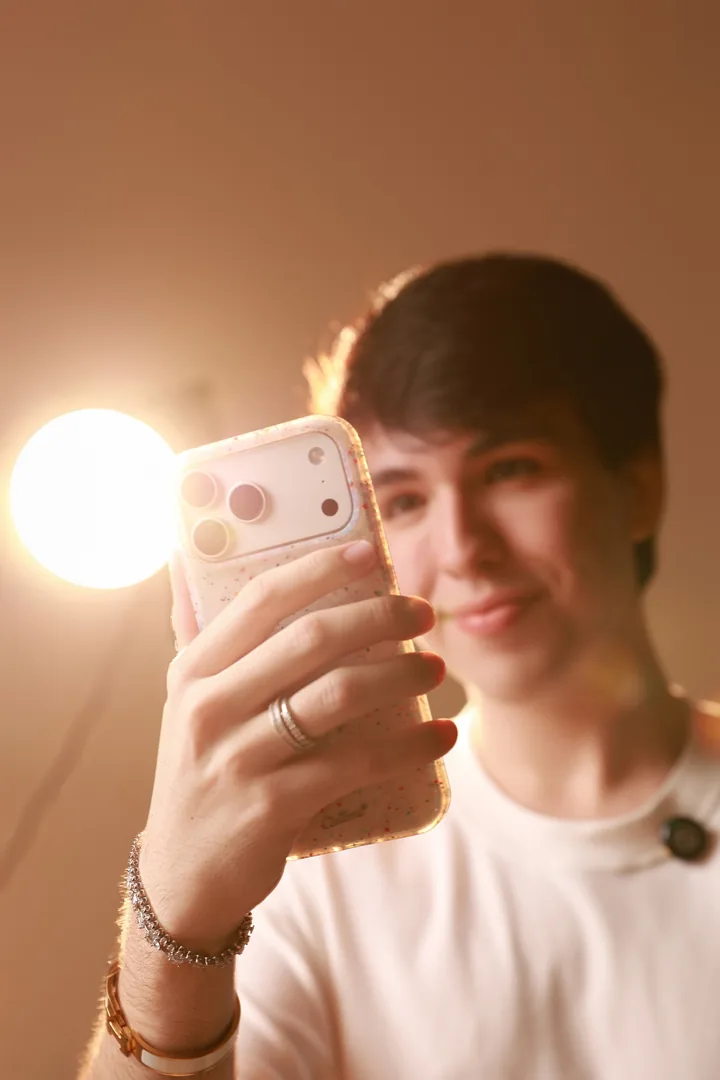 Fernando Martin usando o celular sob a luz quente do estúdio