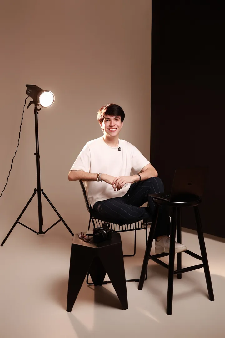 Fernando Martin sentado ao lado da iluminação e do notebook no estúdio