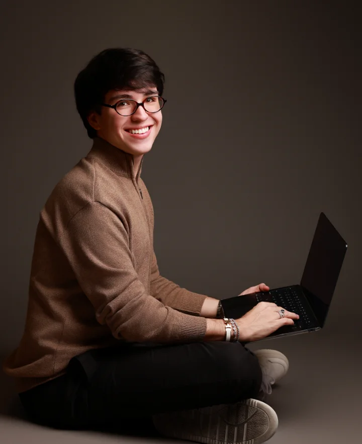 Fernando Martin de blusa marrom, sorrindo com o notebook